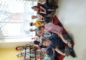 Dzieci słuchają opowiadania czytanego przez bibliotekarkę